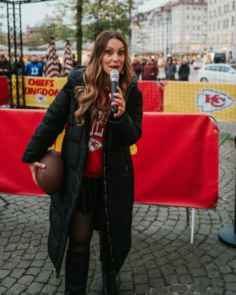 Stephy moderiert mit Mikrofon und Football im Chiefs Kingdom